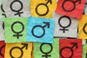 Crumpled colorful paper notes with gender symbols.